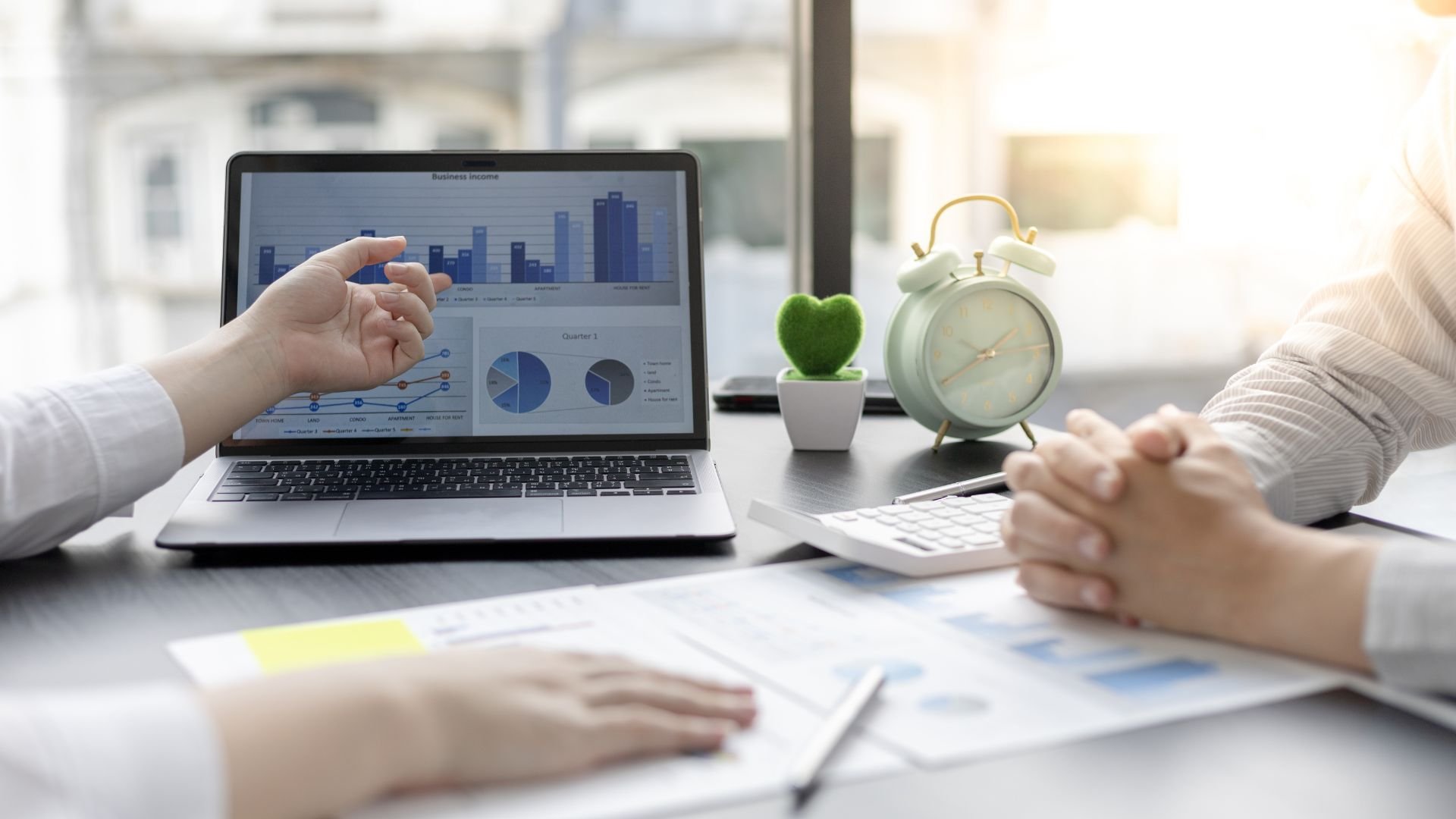 Business meeting with laptop showing financial charts and graphs