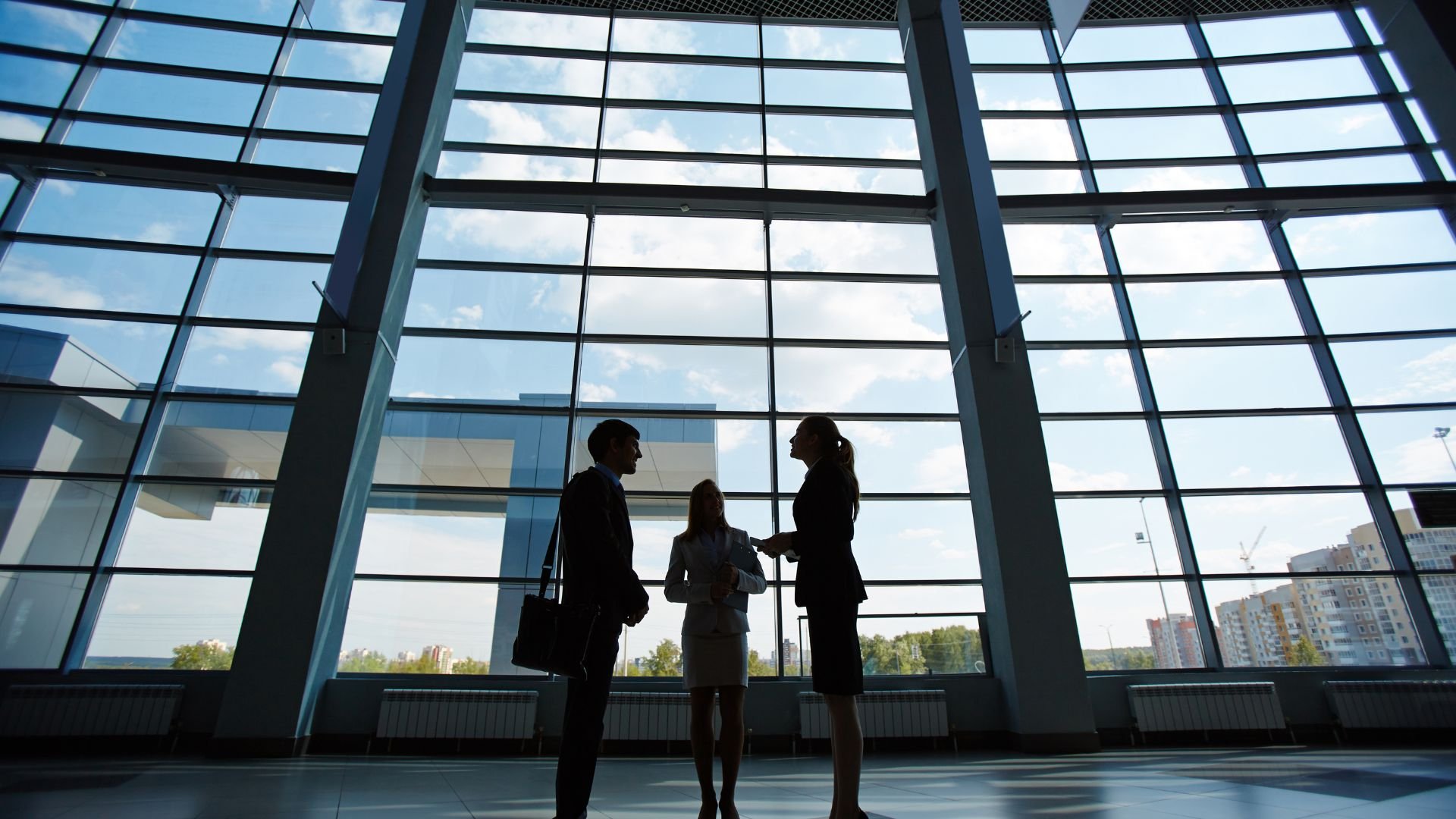 Business colleagues discussing in modern office with large glass windows