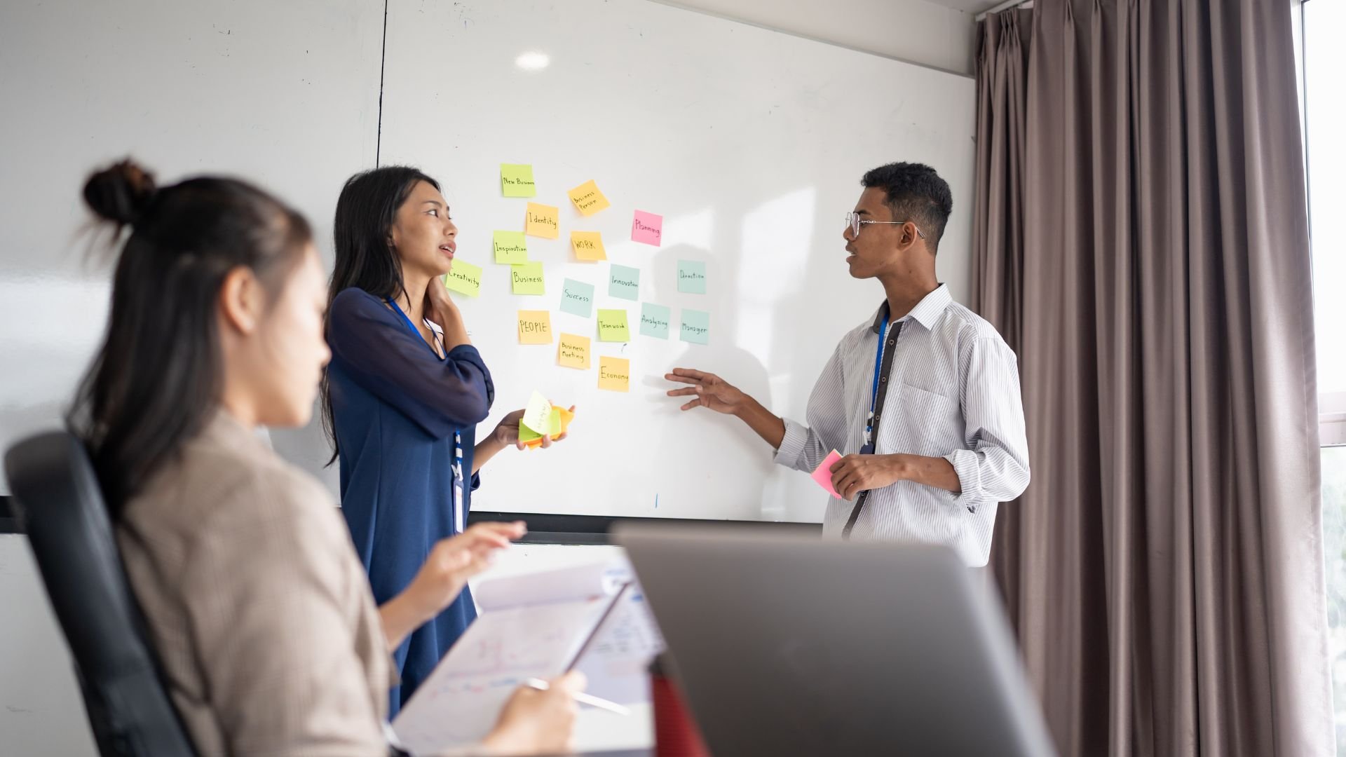 Team brainstorming with sticky notes on whiteboard during meeting